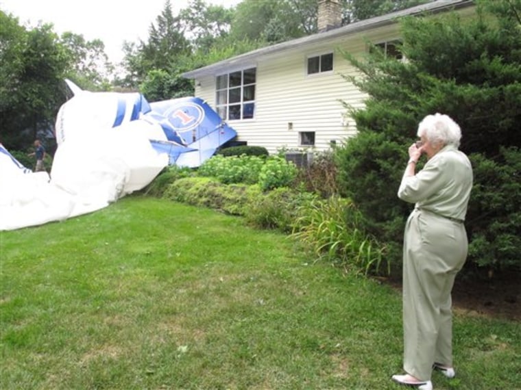 Lillian Bernhagen takes photos of a blimp that broke free of its moorings at an airport and landed in her backyard on Sunday, Aug. 14, 2011, in Worthington, Ohio. (AP Photo/Kantele Franko)